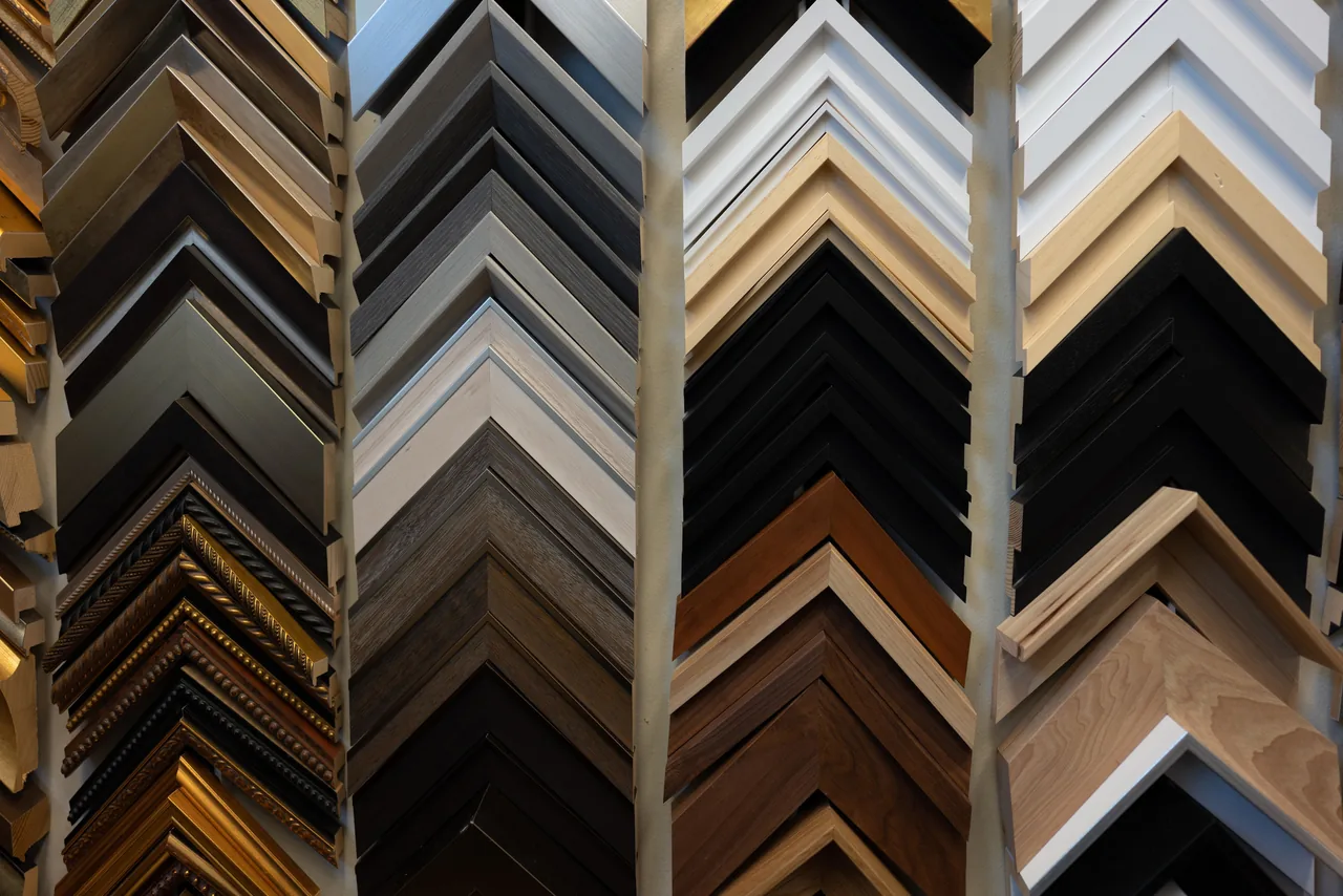 A wall of custom frame moulding samples at Dallas Frame & Gallery by Max