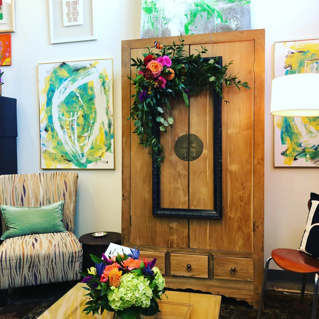 Framed art and a floral shadow box installed in a colorful room