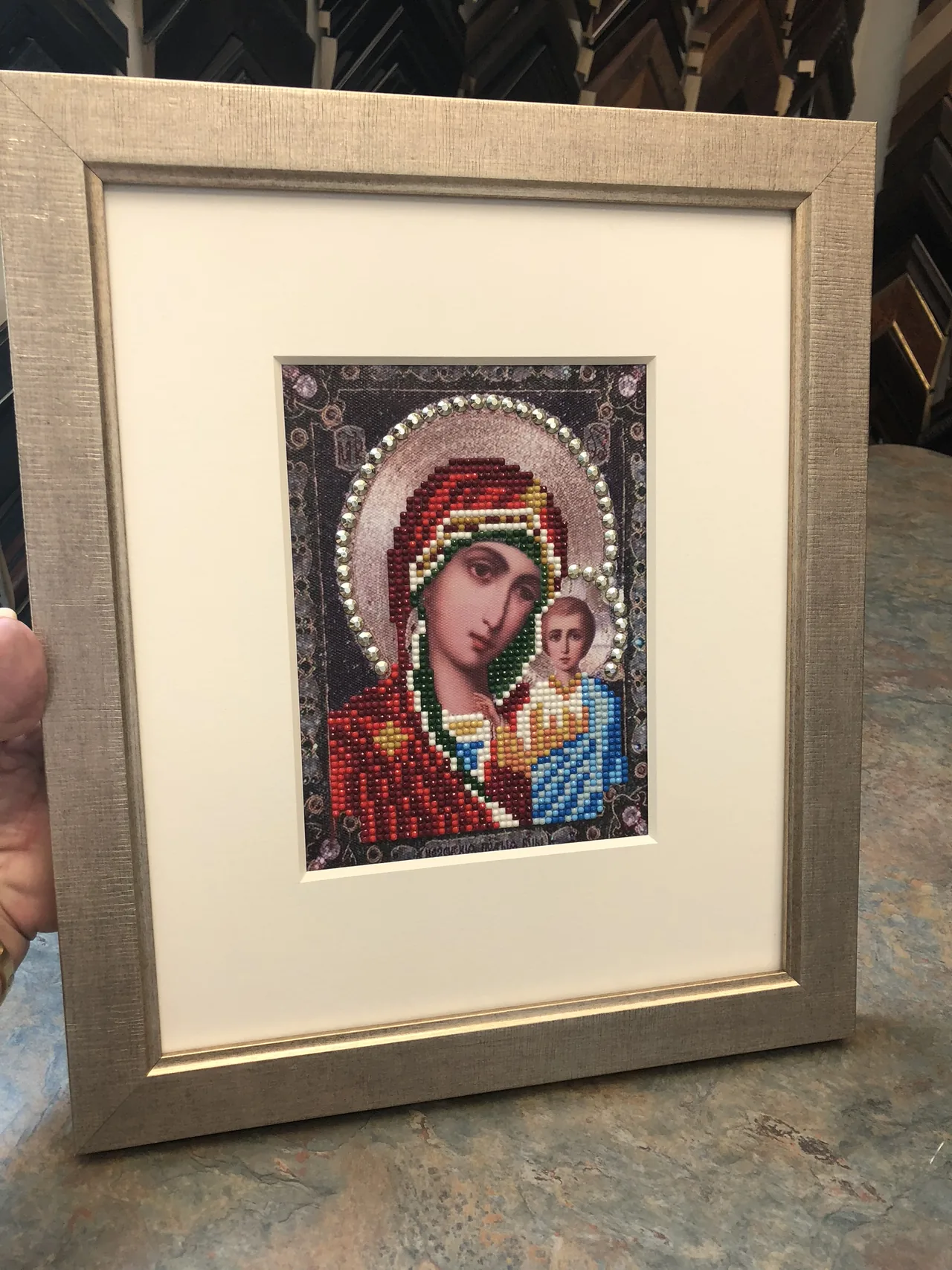 Small religious needlework in a neutral frame
