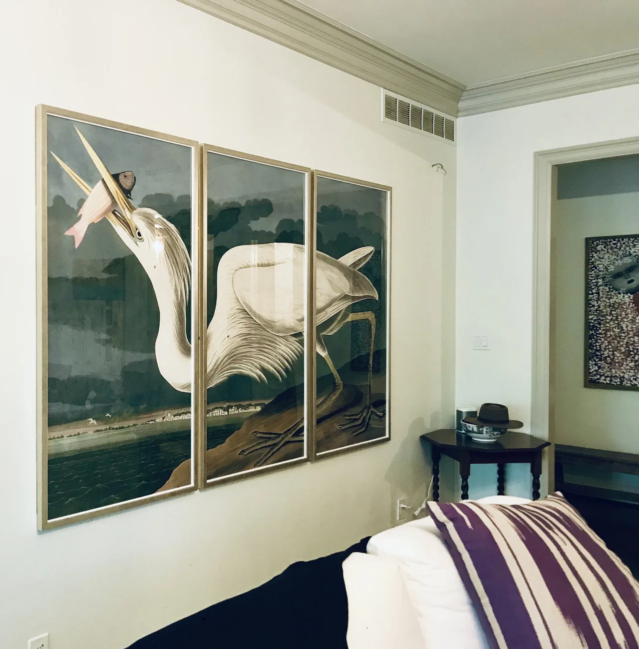 A framed bird triptych installed in a bedroom
